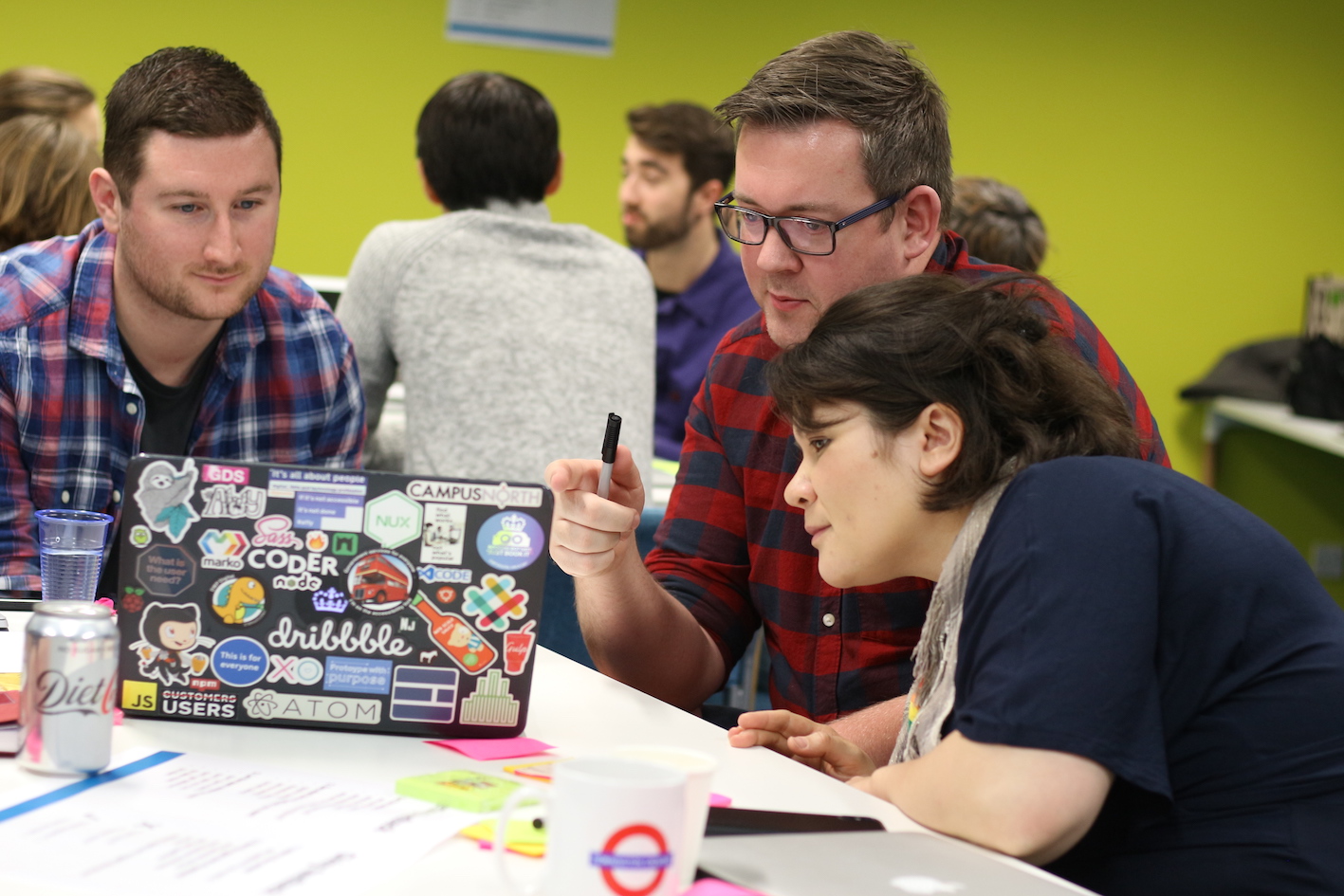 An image of 3 people in discussion around a laptop