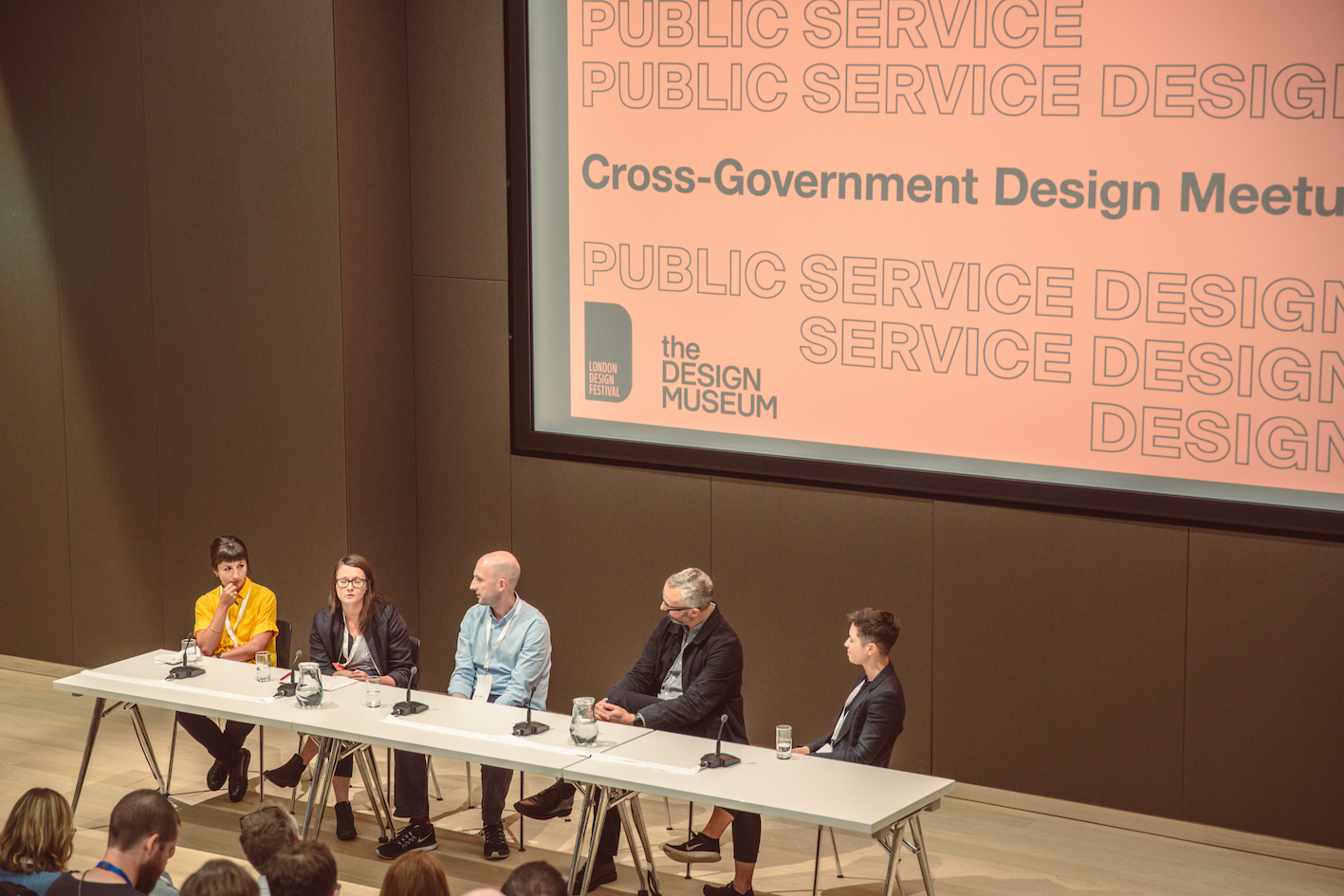 Five people sitting at a table in front of a screen saying 'Cross-Government Design Meetup'