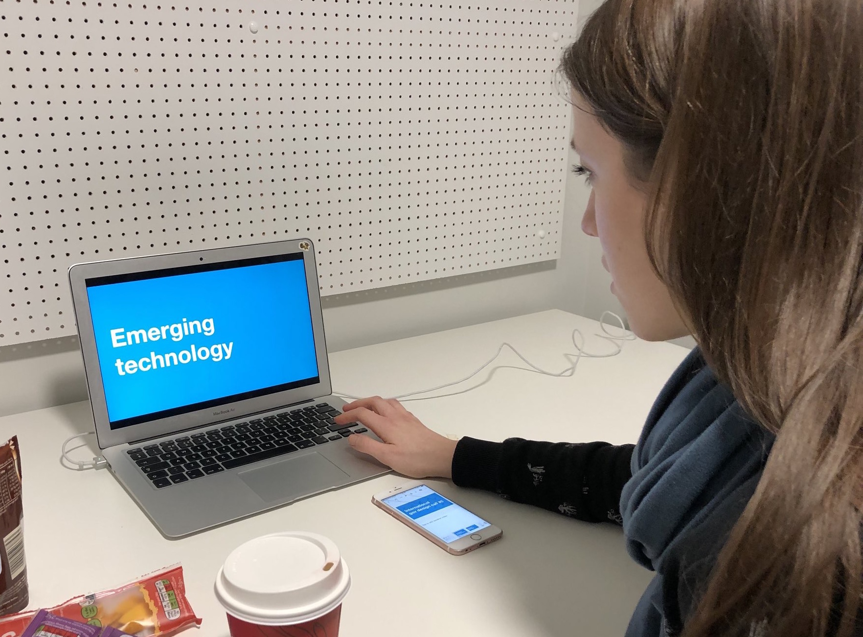 A woman at a laptop with a mobile phone