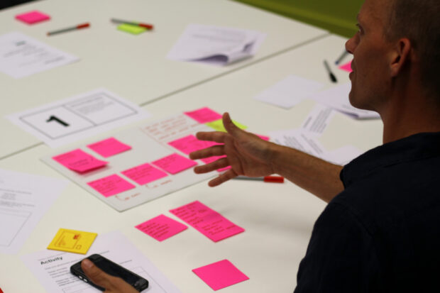 Someone working at a table with Post-it notes and pieces of paper