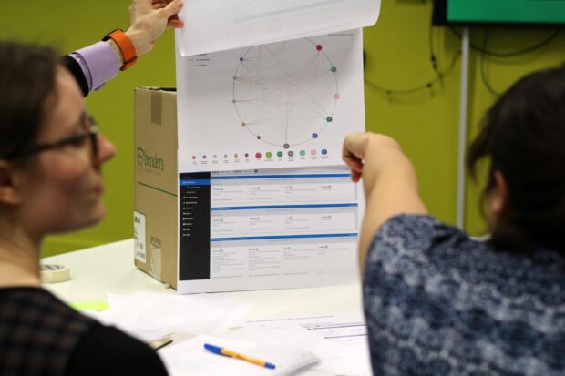 a person pointing at a chart, sitting with her back to the camera, another person looking at her