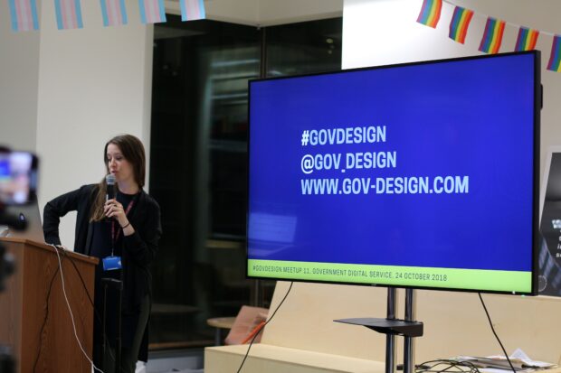 an image of a presenter with a microphone and a screen saying '#GOVDESIGN, @GOV_DESIGN, WWW.GOVDESIGN.COM'