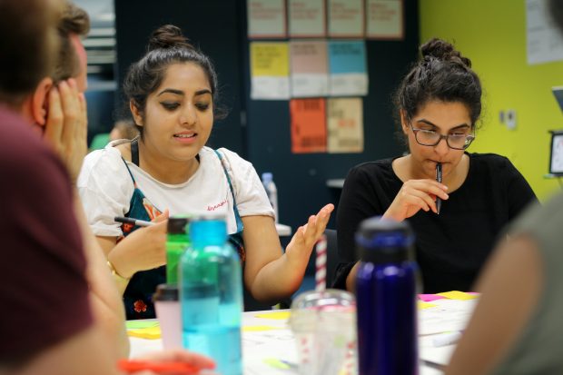 A group of participants in GDS design training working together at a table – two female participants with darker skin tones in focus 