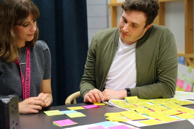 Ignacia Orellana, senior service designer at GDS, and Leon Hubert, user researcher at GDS, sitting at a table analysing the user research findings gathered