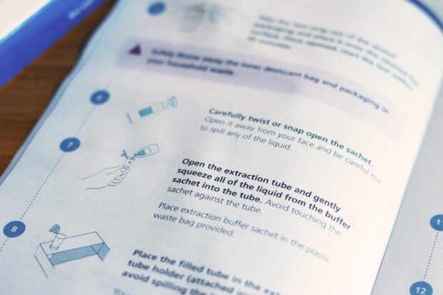 A closeup of the step-by-step guide for COVID-19 self-testing showing a multi-step description of how to test with illustrations and short descriptions