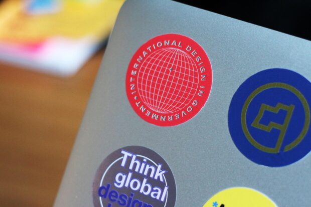 Multiple stickers on a laptop computer, the one in focus says: International design in government