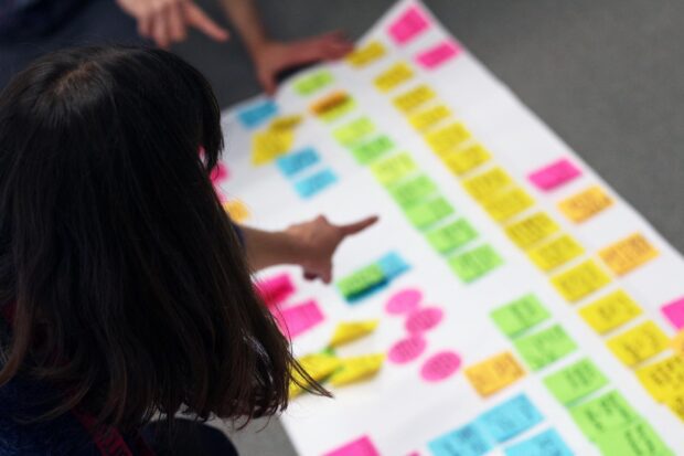 Two people pointing at a journey map for being a designer at the Government Digital Service