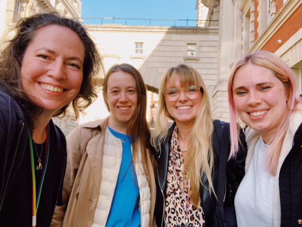 Four heads of design in government stood in the street smiling at the camera. From left to right in the photo we have Nikola Goger (Ministry of Justice), Kara Kane (GDS), Sophie Boyd (DHSC/NHS England), Laura Yarrow (GDS).